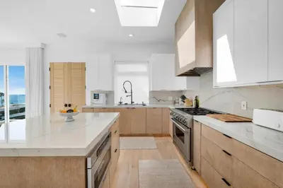 a kitchen with white counter tops and wooden cabinets at Moonstone Beach House Oceanview Luxe Retreat in Manhattan Beach
