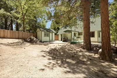 a house with a playground in a yard with trees at Cozy Cabin Retreat with a Hot Tub in Running Springs