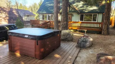a hot tub sitting on a deck in front of a house at Cozy Cabin Retreat with a Hot Tub in Running Springs