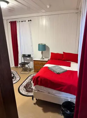 a bedroom with a red bed and a table with a lamp at Naryn Guest House 3 in Los Angeles