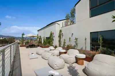 a patio with white chairs and tables and a building at Blueground East Hollywood rooftop nr Griffith Park LAX-1335 in Los Angeles