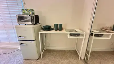 a microwave on top of a refrigerator next to a table at Cozy stay by Anatolian in Los Angeles