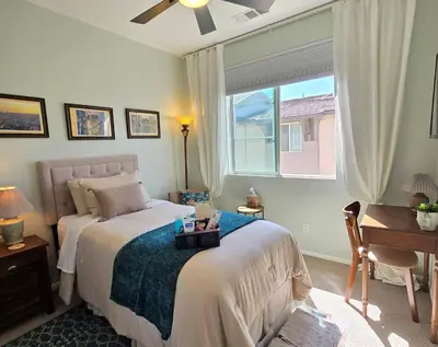 a bedroom with a bed and a window and a desk at The Savi Suite in Corona