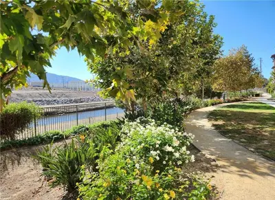 a garden with a path next to a body of water at The Savi Suite in Corona