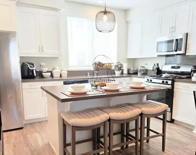 a kitchen with white cabinets and a island with bar stools at The Savi Suite in Corona
