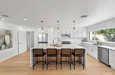 a white kitchen with a large kitchen island with chairs at Ocean View Luxury 5BR Modern Coastal Home in Rancho Palos Verdes