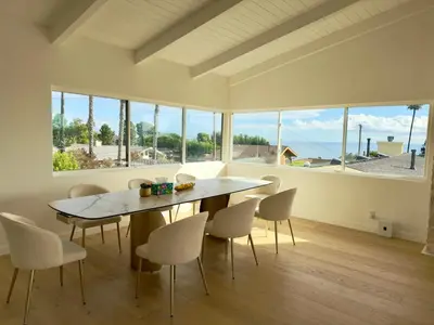 a dining room with a table and chairs and windows at Ocean View Luxury 5BR Modern Coastal Home in Rancho Palos Verdes