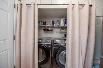 a laundry room with two washing machines and curtains at Welcome to your home at the Orange Circle in Orange