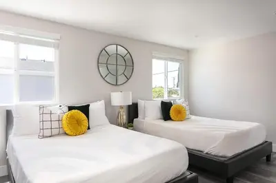 two beds in a bedroom with white walls and windows at Spacious Home Central Area Airport Free Parking in Burbank