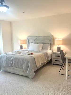 a bedroom with a white bed with two lamps and a chair at Spacious 3BR 3BA Home 3 Car Garage Garden Near DTLA Pasadena Hollywood in Alhambra