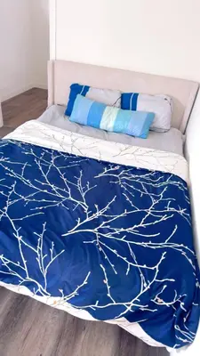 a bed with a blue blanket with a tree design at Huge bedroom with shared bathroom in Ontario