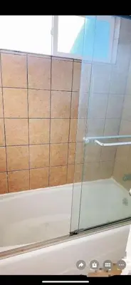 a shower with a glass door on a bath tub at Huge bedroom with shared bathroom in Ontario