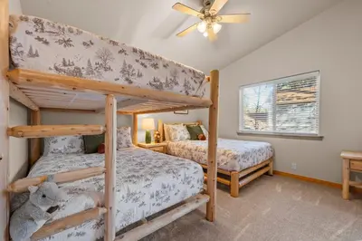a bedroom with two bunk beds and a ceiling fan at Pine Cottage - NEW! Shuffleboard, Pool Table, Smart TVs, Fenced Yard in Big Bear Lake