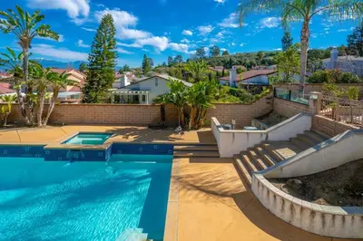 a swimming pool with two chairs next to a house at Marbella Lane - Captivating Home w Pool in Rowland Heights