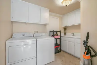 a kitchen with white cabinets and a washer and dryer at Marbella Lane - Revitalizing Getaway w Pool in Rowland Heights