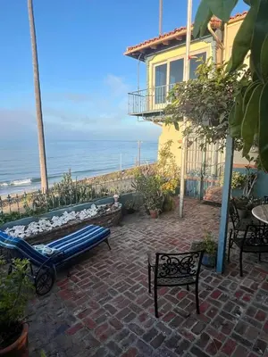 a patio with a blue bench and a house and the ocean at Villa Porto Marina - Oceanfront Living in Castellammare