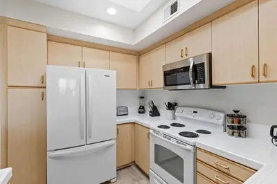 a kitchen with white appliances and wooden cabinets at The Nautilus Waterfront Retreat Marina View, Pool Sauna Gym Jacuzzi in Los Angeles
