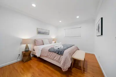 a white bedroom with a bed and a chair at Marbella Lane - Serene and Pristine 2BR Home in West Covina