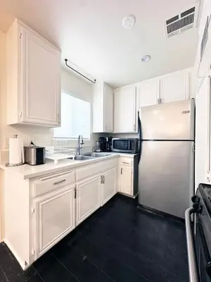 a kitchen with white cabinets and a stainless steel refrigerator at 2BR Bohemian Haven Near Walk of Fame - BR6 - BUR in Burbank