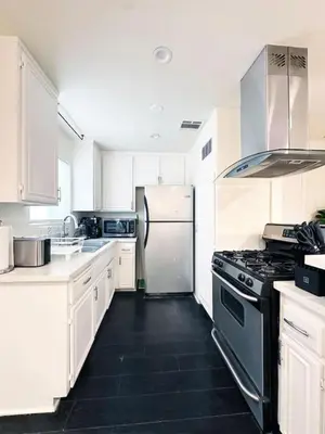 a kitchen with white cabinets and a stove and refrigerator at 2BR Bohemian Haven Near Walk of Fame - BR6 - BUR in Burbank