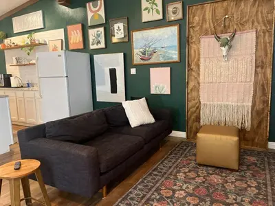 a living room with a black couch and a green wall at LA Beach City Studio in Harbor City