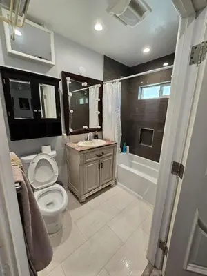 a bathroom with a toilet and a sink and a tub at Entire Luxurious Vaulted Haven with Pool in Tarzana