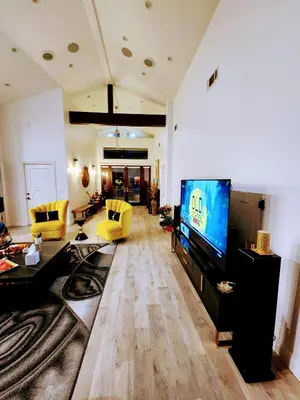 a living room with a flat screen tv and yellow chairs at Entire Luxurious Vaulted Haven with Pool in Tarzana