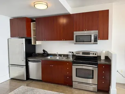 a kitchen with stainless steel appliances and wooden cabinets at Furnished Studio Apartment in Los Angeles