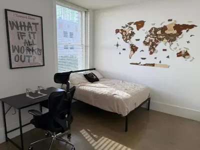 a bedroom with a bed and a desk and a world map on the wall at Furnished Studio Apartment in Los Angeles