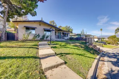a house with a grassy yard in front of it at 1 Mi to LLUMC! Loma Linda Home with Shared Patio in Loma Linda