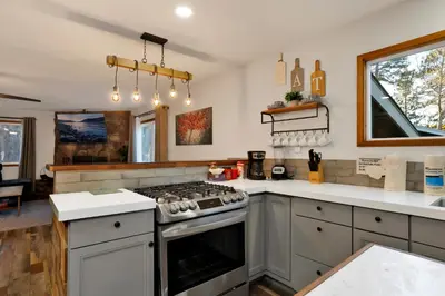 a kitchen with a stove top oven next to a window at The Highland Getaway at Big Bear Village | Downtown Modern Retreat Cottage in Big Bear Lake