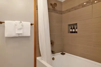 a bathroom with a shower with a tub and a sink at The Highland Getaway at Big Bear Village | Downtown Modern Retreat Cottage in Big Bear Lake