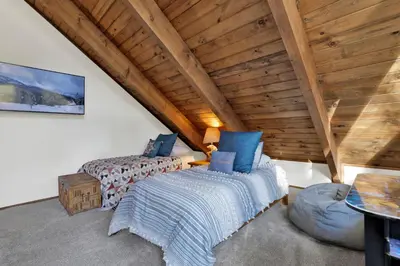a bedroom with a bed and a chair in a attic at Willow Bear Lodge: Shuttle Stop Pet-Friendly, Walk to the Lake | Book Your Big Bear Stay! in Big Bear Lake