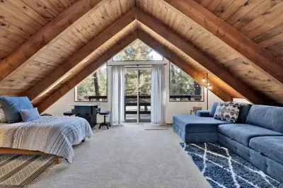a attic bedroom with a bed and a couch at Willow Bear Lodge: Shuttle Stop Pet-Friendly, Walk to the Lake | Book Your Big Bear Stay! in Big Bear Lake