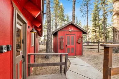a red shed with a red door next to a fence at Willow Bear Lodge: Shuttle Stop Pet-Friendly, Walk to the Lake | Book Your Big Bear Stay! in Big Bear Lake