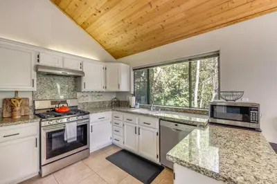 a kitchen with white cabinets and a large window at 2 Decks! Pet-Friendly Lake Arrowhead Cabin in Lake Arrowhead