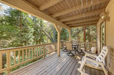 a wooden deck with chairs and a table on it at 2 Decks! Pet-Friendly Lake Arrowhead Cabin in Lake Arrowhead