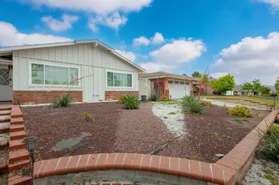 a house with a brick fence in front of a yard at Marbella Lane - Serene & Spacious 3BR Haven in West Covina