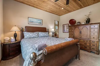 a bedroom with a large bed and a dresser at Boulder Cove։ Lakefront Estate in Big Bear Lake