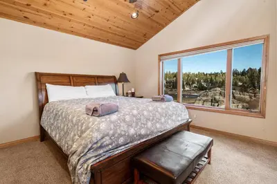 a bedroom with a bed and a large window at Boulder Cove։ Lakefront Estate in Big Bear Lake