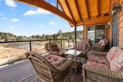 a screened porch with wicker chairs and a table at Boulder Cove։ Lakefront Estate in Big Bear Lake