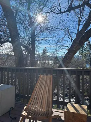 a wooden bench sitting on a deck with the sun at Lakeview Mountain Modern in Lake Arrowhead