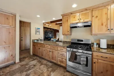 a kitchen with wooden cabinets and a stove top oven at The Hidden Pines Mountain Home by Navigate Stays in Running Springs