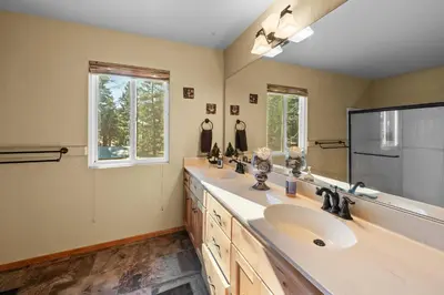 a bathroom with two sinks and a large mirror at The Hidden Pines Mountain Home by Navigate Stays in Running Springs