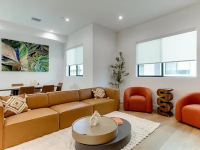 a living room with a brown couch and orange chairs at Modern Luxe Retreat Four-Bedroom in Los Angeles