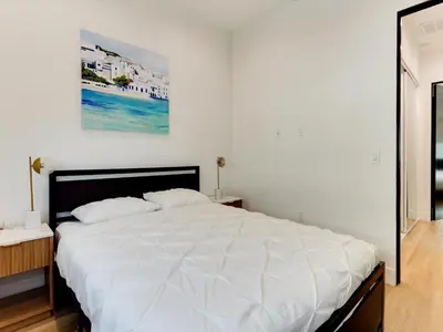 a white bed in a bedroom with a painting on the wall at Modern Luxe Retreat Four-Bedroom in Los Angeles