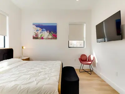 a bedroom with a white bed and a red chair at Modern Luxe Retreat Four-Bedroom in Los Angeles