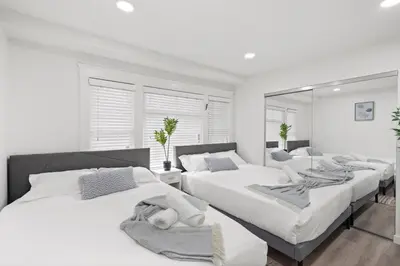 a white bedroom with two beds and a mirror at 1 mile from the Beach Fire Pit, Patio, Parking! in Long Beach