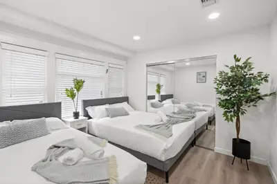 a white bedroom with two beds and a mirror at 1 mile from the Beach Fire Pit, Patio, Parking! in Long Beach