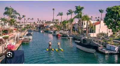 two people on paddle boards in a river with boats at 5 STAR BEAUTIFUL LONG BEACH HOuSE in Long Beach